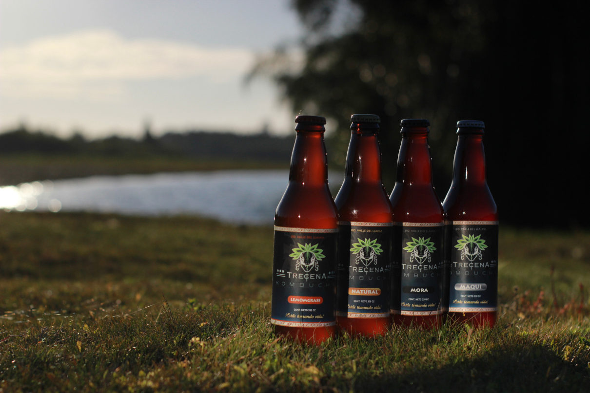 Botellas de kombucha Trecena junto al río al atardecer